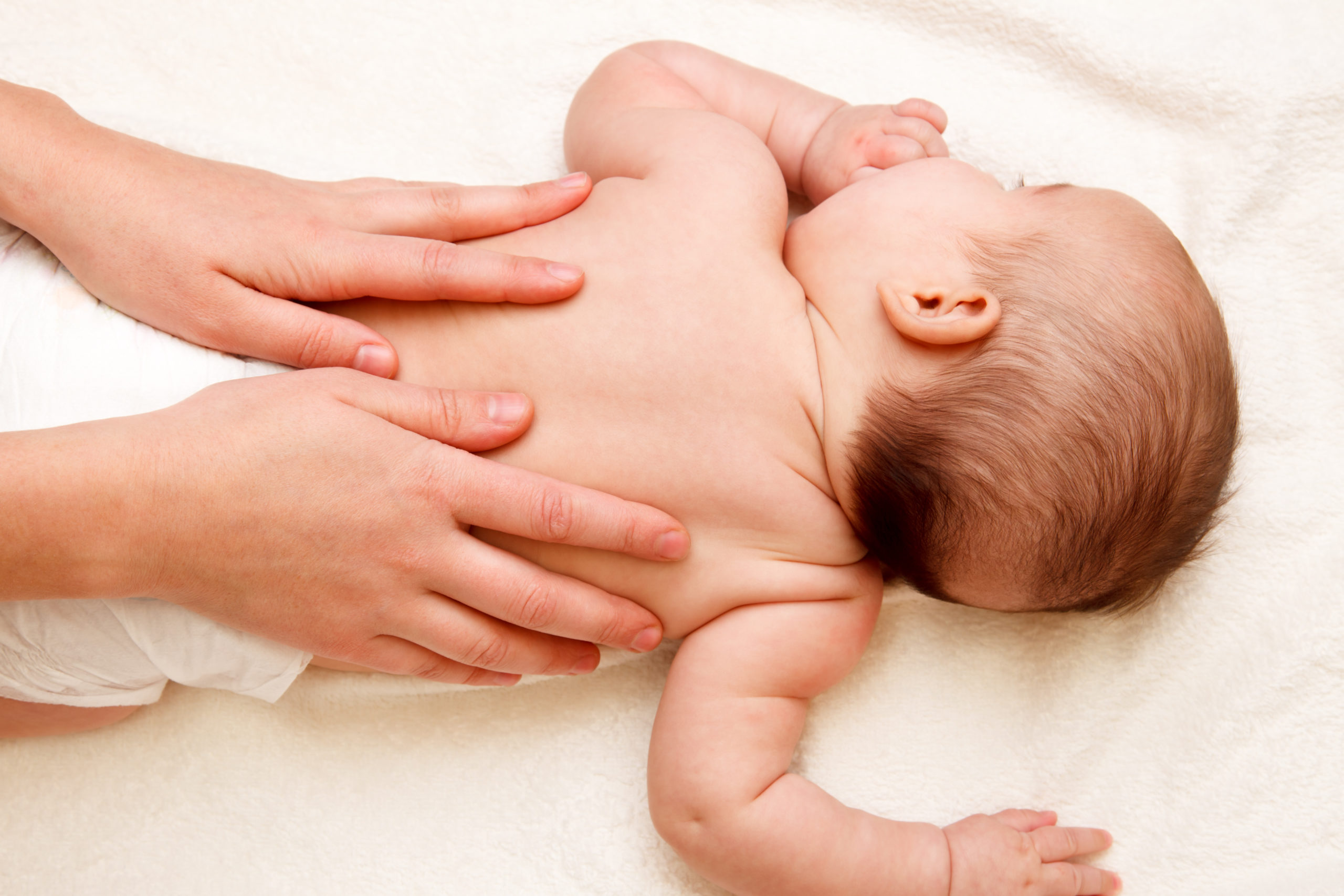 Babymassage Hände auf Babys Rücken